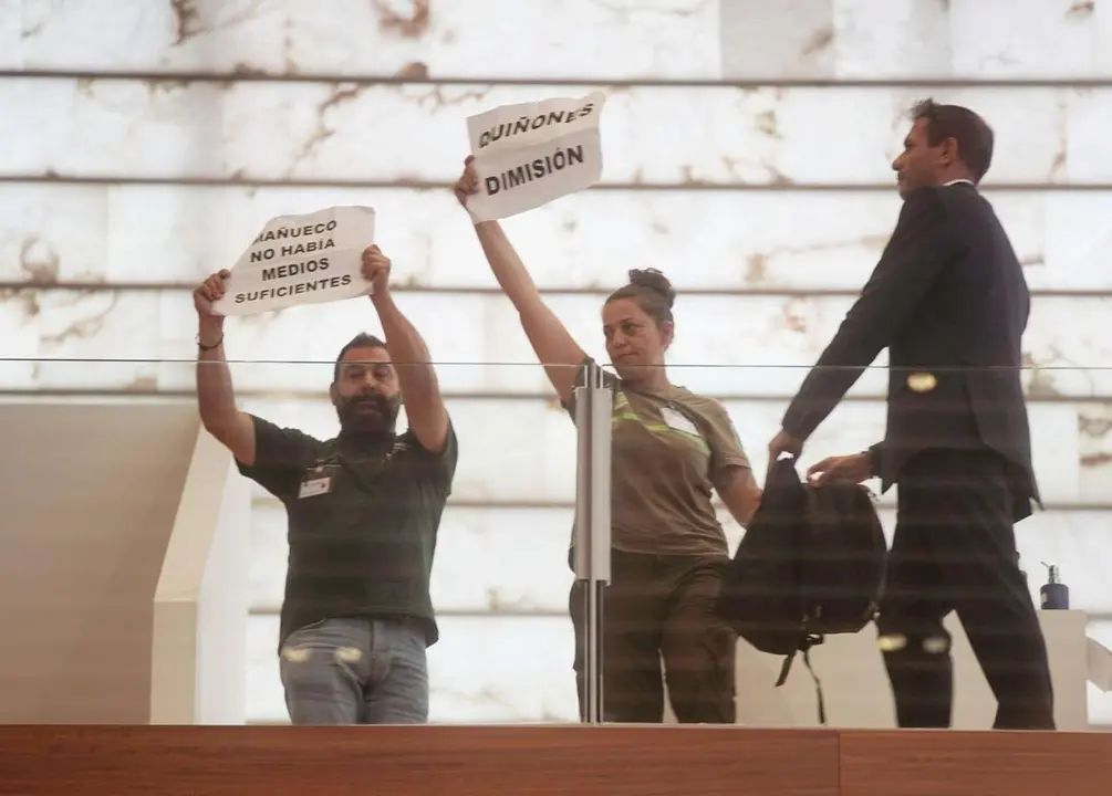 Rub&eacute;n Cacho. ICAL. Dos bomberos forestales muestran pancartas durante el  Pleno extraordinario de las Cortes